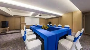 A conference room with a long table, white chairs, and a blue tablecloth. - Wassim Hotel Fushun Yantan (Zigong)