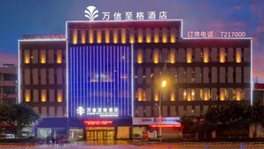 A hotel with a modern facade, illuminated signage, and a contact number for booking. - Wassim Hotel Fushun Yantan (Zigong)