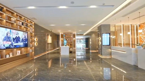 A modern hotel lobby with a long reception desk, a TV screen, and a marble floor. - Wassim Hotel Fushun Yantan (Zigong)