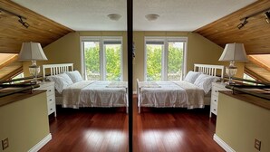 Une pièce aux murs recouverts de miroirs, avec deux lits, de grandes fenêtres, des poutres en bois au plafond et un plancher en bois.