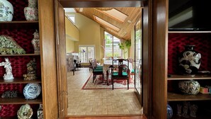 Un espace repas doté d’un plafond en bois, d’un parquet en point de Hongrie et offrant une vue sur l’extérieur grâce à de grandes fenêtres.