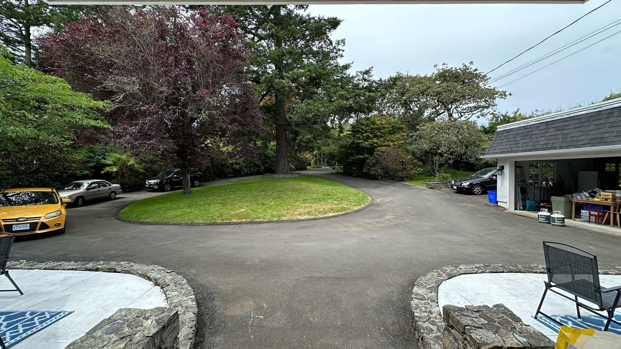 Une allée menant à une propriété résidentielle, avec une allée circulaire, un garage et une pelouse.