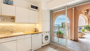 Cocina moderna con lavadora, un lavamanos y vistas al mar a través de un ventanal.