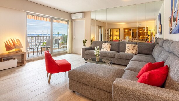 Una sala de estar moderna con un sofá gris, una silla roja y una mesa de centro de vidrio.