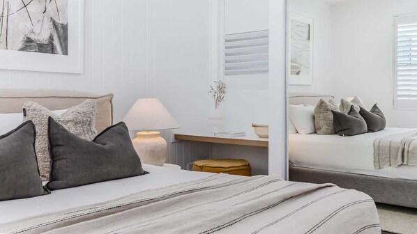 Une chambre à coucher avec un lit, une table de chevet, une lampe et un miroir qui reflète la pièce.
