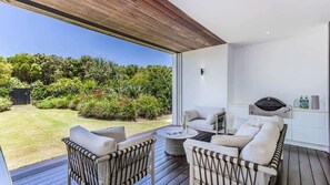 A modern outdoor living space with a sofa, chairs, and a grill.