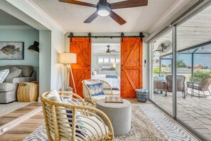 A room with a ceiling fan, wicker furniture, a bed, and a view through large sliding doors to an outdoor patio. - Private Fishing Dock: Waterfront Palmetto Home! (Palmetto)