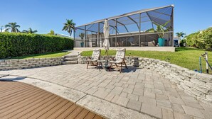 A modern outdoor patio with a glass enclosure, stone seating, and a wooden deck. - Private Fishing Dock: Waterfront Palmetto Home! (Palmetto)
