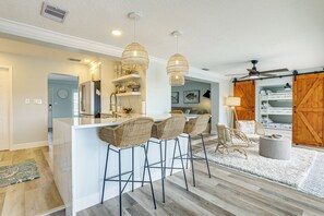 Une cuisine moderne dotée d’un îlot central, de tabourets de bar et de luminaires suspendus.