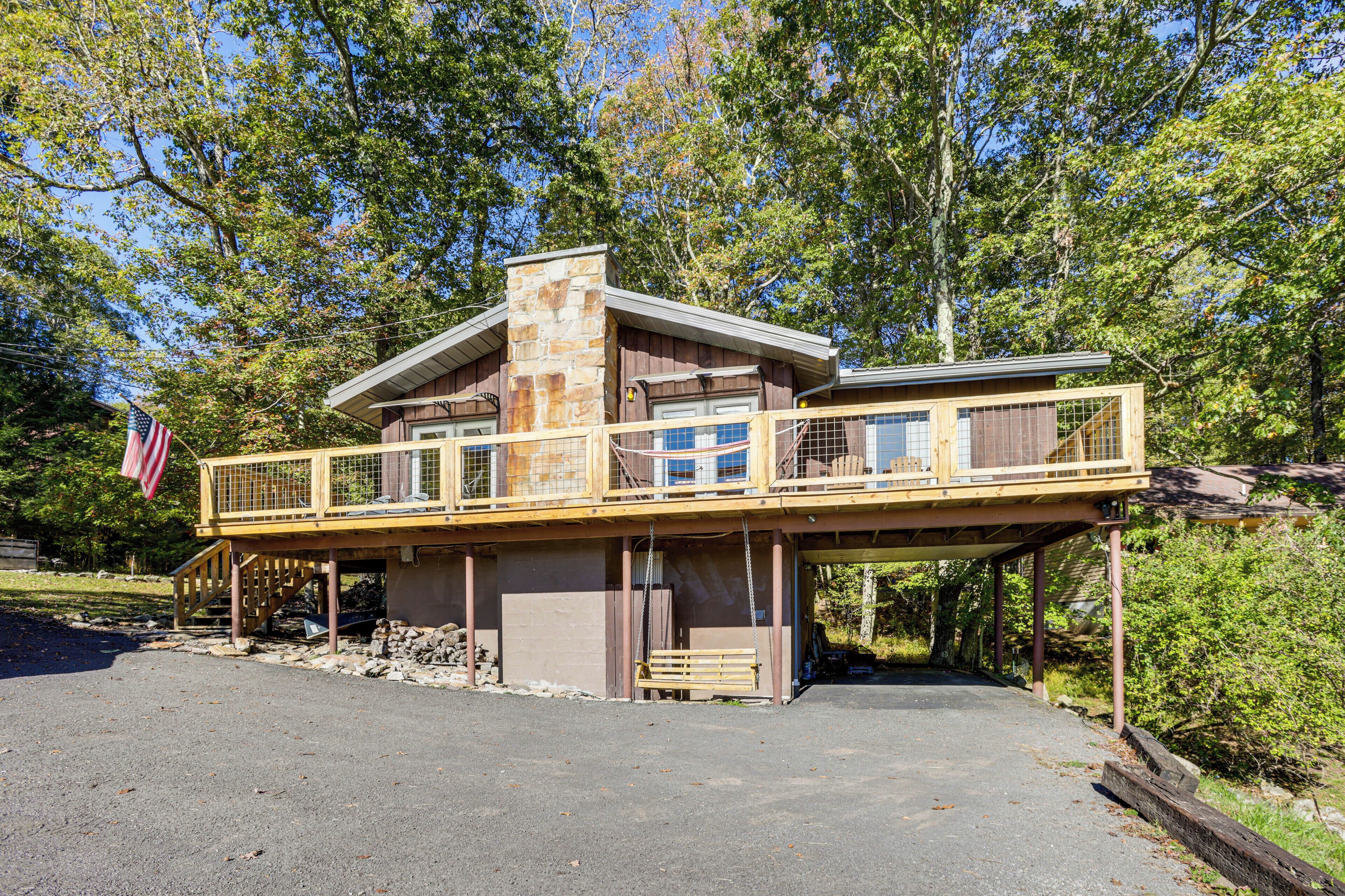 Une cabane à deux étages dotée d’un balcon, d’une cheminée en pierre et d’un drapeau américain.