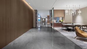 A modern hotel corridor with a dining area featuring a round table and chairs, recessed ceiling lighting, and a polished floor. - Grand Madison LongHua Yujing Shenzhen (Shenzhen)