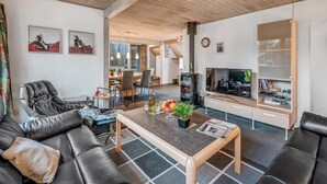 Un salon moderne doté d’une cheminée, de canapés en cuir, d’un coin repas et d’une bibliothèque.
