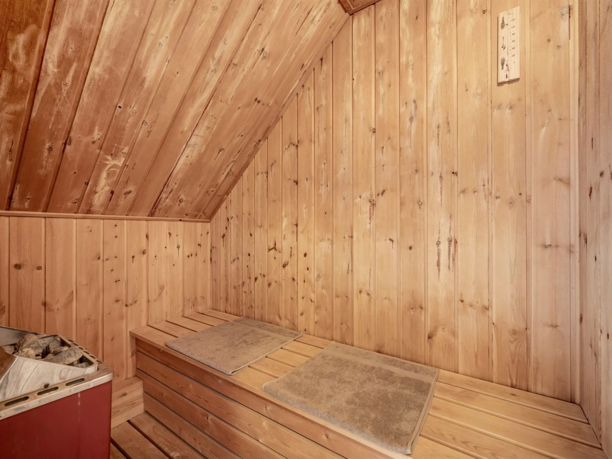 Un sauna en bois avec des bancs et un placard rouge.