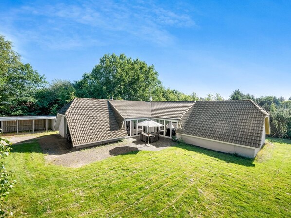 Une maison à deux étages dotée d’un patio couvert et d’une cour clôturée.