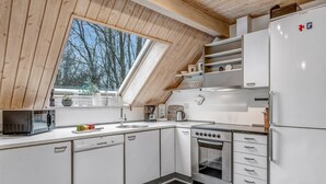 Une cuisine de taille réduite avec un plafond en pente, un four encastré et un réfrigérateur.