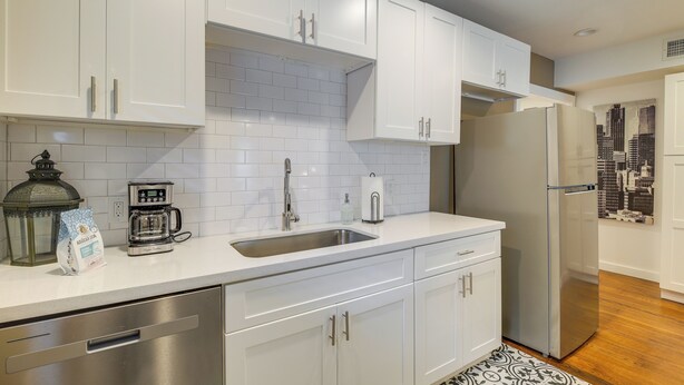 A modern kitchen with white cabinets, a stainless steel sink, a coffee maker, and a refrigerator. - Fourth Ward Apartment: 1 Mi to Downtown Houston! (Houston)