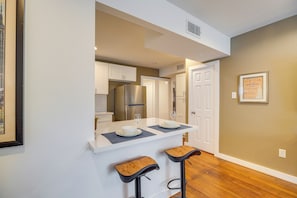 A kitchen with white cabinets, a stainless steel refrigerator, and a white countertop with two bar stools. - 1 Mi to Dtwn, 8 Mi to NRG! Fourth Ward Apt w/ W&D (Houston)