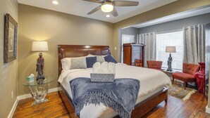 A bedroom with a large bed, a ceiling fan, a nightstand, and a chair. - Fourth Ward Apartment: 1 Mi to Downtown Houston! (Houston)