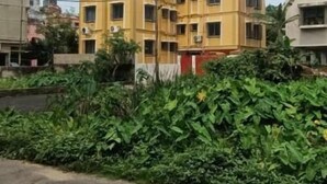 A multi-story yellow building with a central courtyard, surrounded by greenery. - Regencyy Guest House (Kolkata)