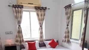 A bedroom with a bed, curtains, a ceiling fan, and a window. - Regencyy Guest House (Kolkata)