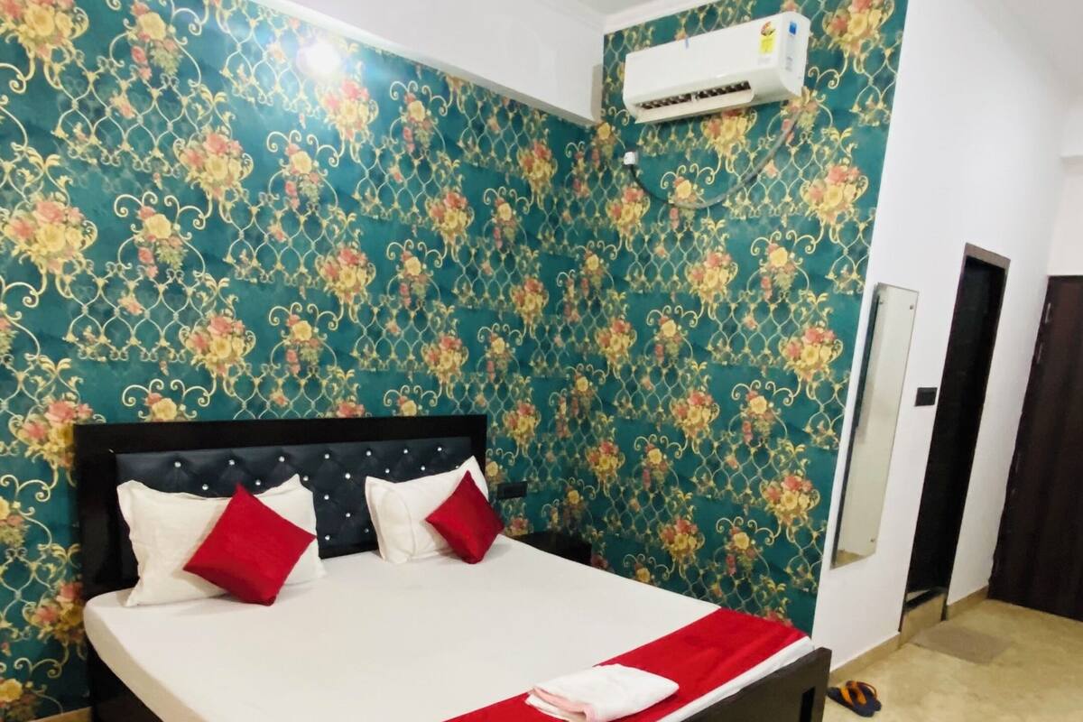Una habitación de hotel con cama, ventilador de techo, equipo de aire acondicionado y puerta.