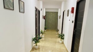 Ένας διάδρομος με γυαλιστερό δάπεδο, γλάστρες με φυτά και φωτογραφίες σε κορνίζες στους τοίχους.