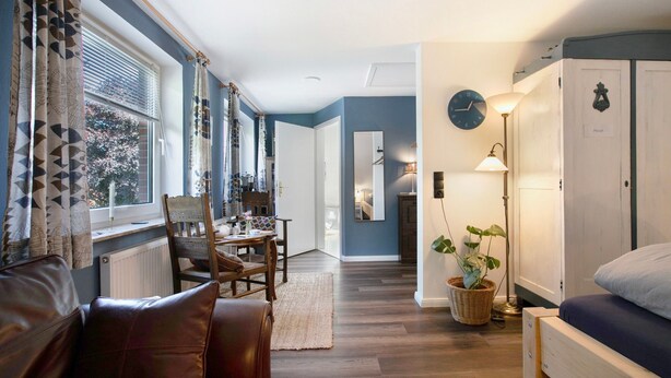Une pièce comprenant un lit, une chaise en bois, une table à manger et une lampe.