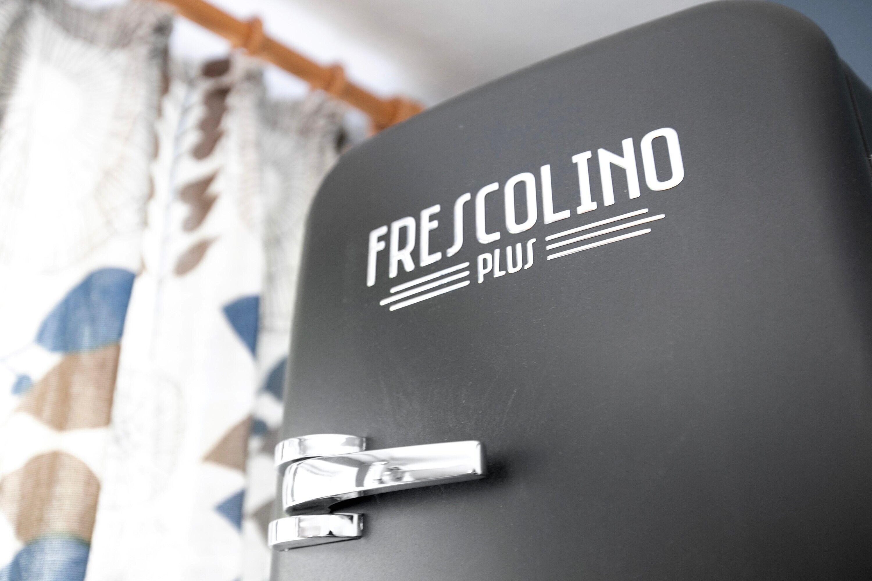 En sort kuffert med teksten 'FRESCOLINO PLUS' og et metalhåndtag.