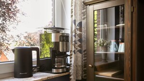 Un comptoir de cuisine avec une machine à café, une bouilloire et un meuble avec des portes en verre.