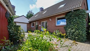 Une maison en briques avec un toit en tuiles, une porte d’entrée et une fenêtre.