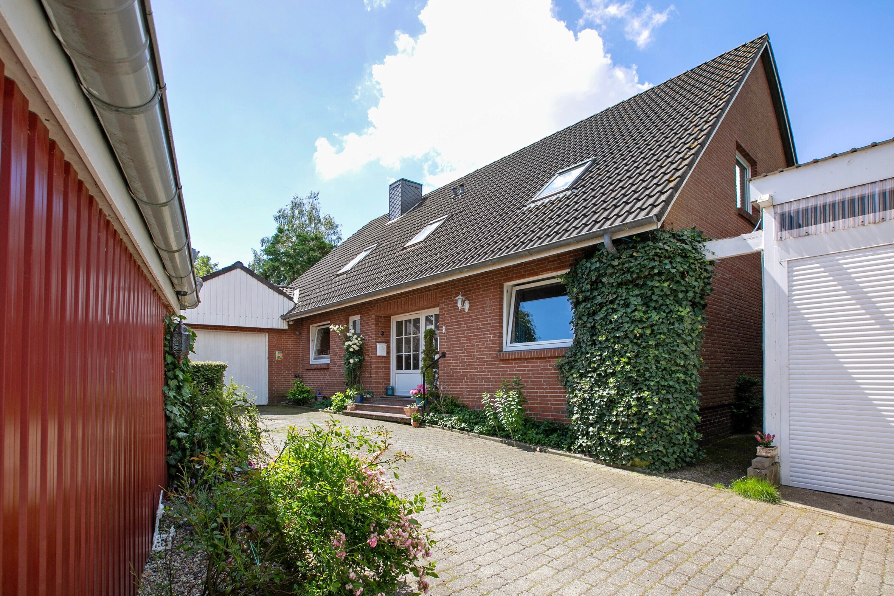 A residential house with a paved driveway, a front door, and a garage.