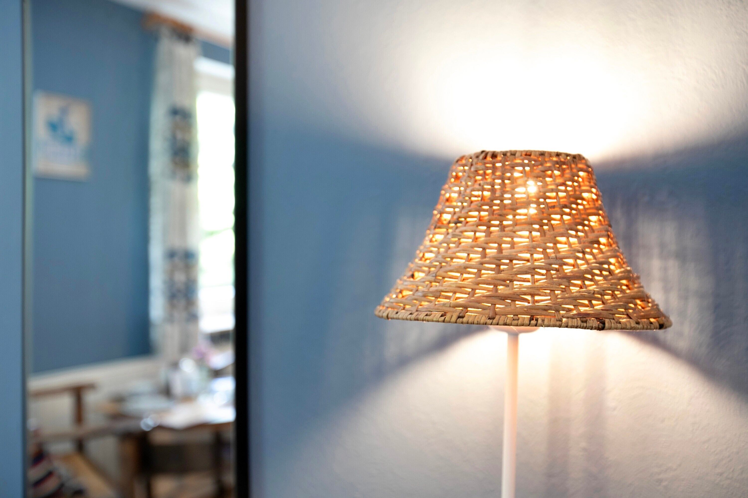 Une lampe tressée adossée à un mur.