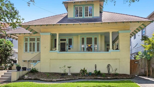 A two-story house with a gabled roof, a front porch, and a small garden area.