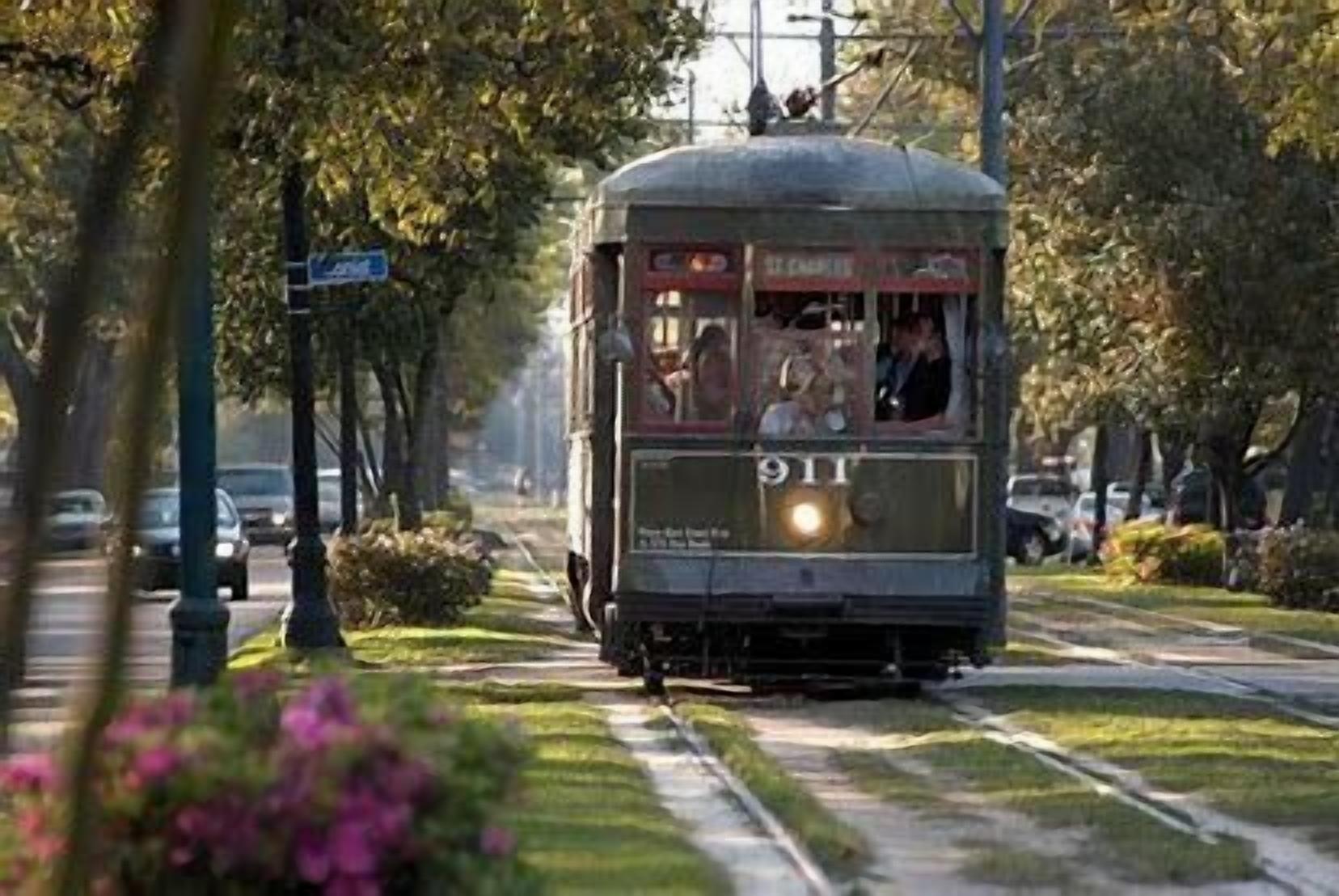 A vintage tram with a vintage design, moving along a tree-lined street.