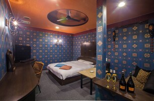 Una habitación con una cama, un escritorio y dos botellas de vino sobre una encimera.