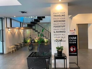 Um hall de hotel moderno com escada, área de estar e placa indicando zona silenciosa.