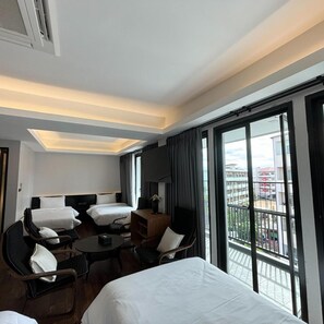 Quarto de hotel com cama, duas cadeiras, uma mesinha e uma televisão.