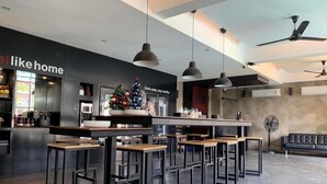 A modern bar area with high tables and chairs, a Christmas tree, and a 'Drink water, stay healthy' sign. - DUM Hotel (Chiang Mai)