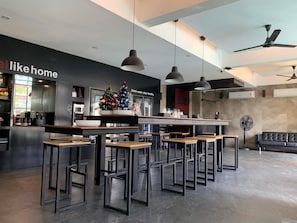 A modern bar area with high tables and chairs, a Christmas tree, and a 'Drink water, stay healthy' sign. - DUM Hotel (Chiang Mai)
