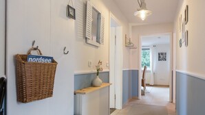 A hallway with a wicker basket, a vase with flowers, a bench, and a door leading to another room. - Apartment 'Ferienwohnung Lillebror' with Shared Terrace, Shared Garden and Wi-Fi (Olderup)