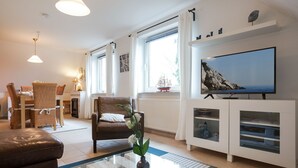 A living room with a television, a dining area with a table and chairs, and a sofa. - Apartment 'Ferienwohnung Lillebror' with Shared Terrace, Shared Garden and Wi-Fi (Olderup)