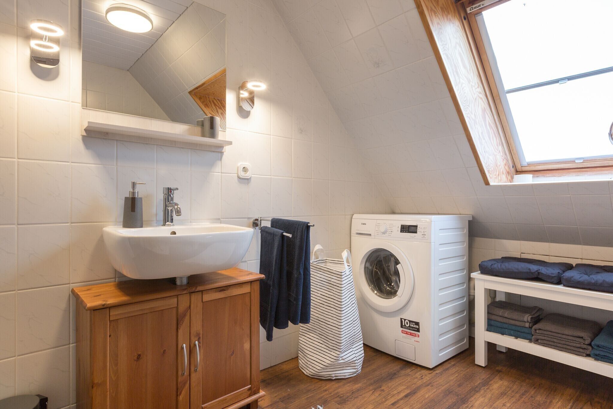 Un bagno moderno e funzionale, con lavabo incassato, lavatrice e un piccolo tavolo con asciugamani piegati.