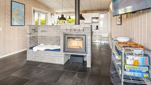 Uma sala de estar moderna com lareira, área de cozinha e espaço para refeições com caixas de pizza.