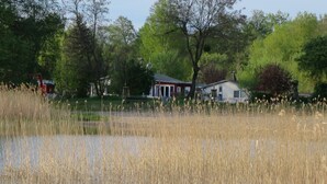 A house with a red roof, surrounded by tall grass and trees.