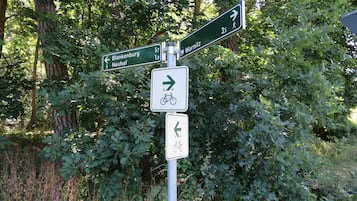 Wegwijzers met pijlen en afstandsmarkeringen, omringd door dichte beplanting.