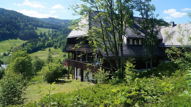 Una casa con un balcone, immersa nel verde e circondata da dolci colline.