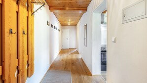 Un corridoio con porte in legno, una ventola a soffitto e una cucina visibile attraverso una porta aperta.