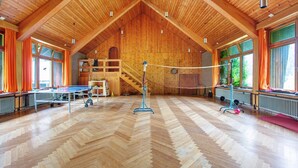 Un'ampia sala con soffitto in legno a volta, un tavolo da ping pong e una rete da pallavolo.