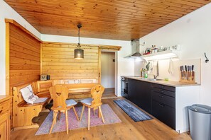 A wooden interior with a dining area, kitchen, and a bench.