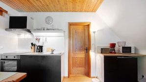 Una cocina compacta con techo de madera, horno empotrado, microondas y un lavamanos.